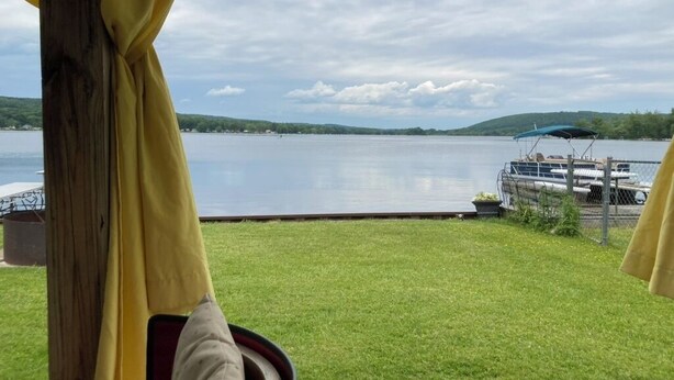 Vista de un lago con un muelle y una zona verde al frente.