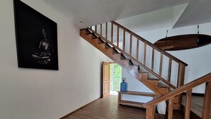 Un escalier en bois menant à l’étage supérieur, un distributeur d’eau et une porte donnant sur un espace extérieur.