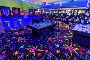 Enjoy a game of pool in this lively room with a pool table, star-patterned carpet, and cityscape curtains.