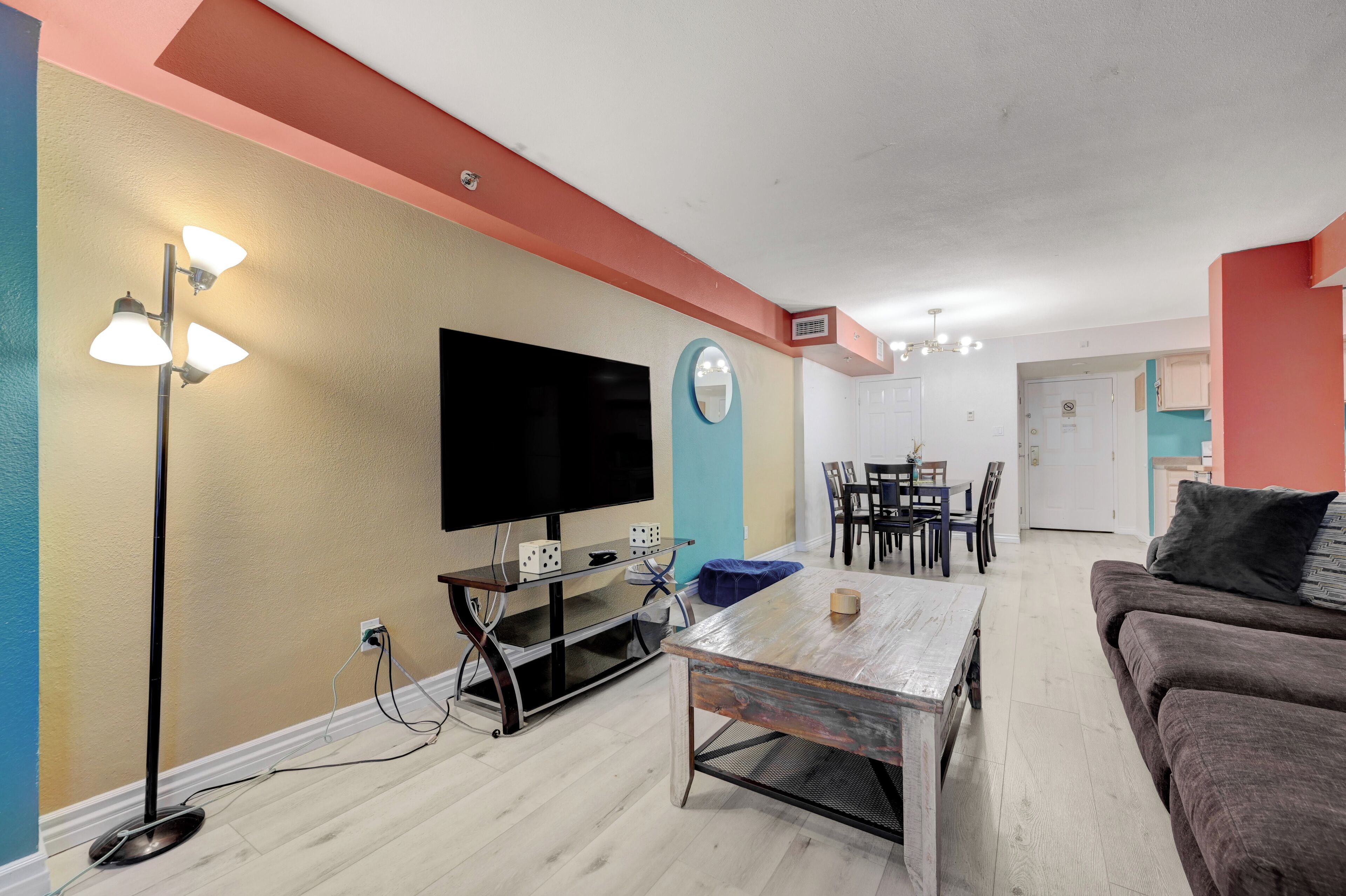 Una sala de estar con televisión de pantalla plana, una mesa de centro, un sofá y un comedor con sillas y una mesa.