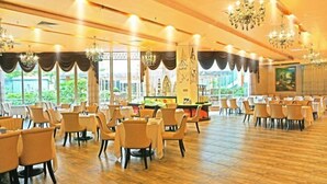 A spacious dining area with multiple tables and chairs, large windows, and chandeliers. - University Town International Hotel (Guangzhou)