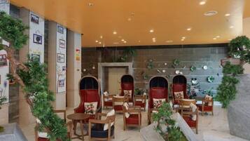 Una hall d'hotel con aree relax, un camino e piante ornamentali.