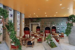 A hotel lobby with seating areas, a fireplace, and decorative plants. - University Town International Hotel (Guangzhou)