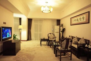 A hotel room with a television, a sofa set, a table, a lamp, and a decorative plant. - University Town International Hotel (Guangzhou)