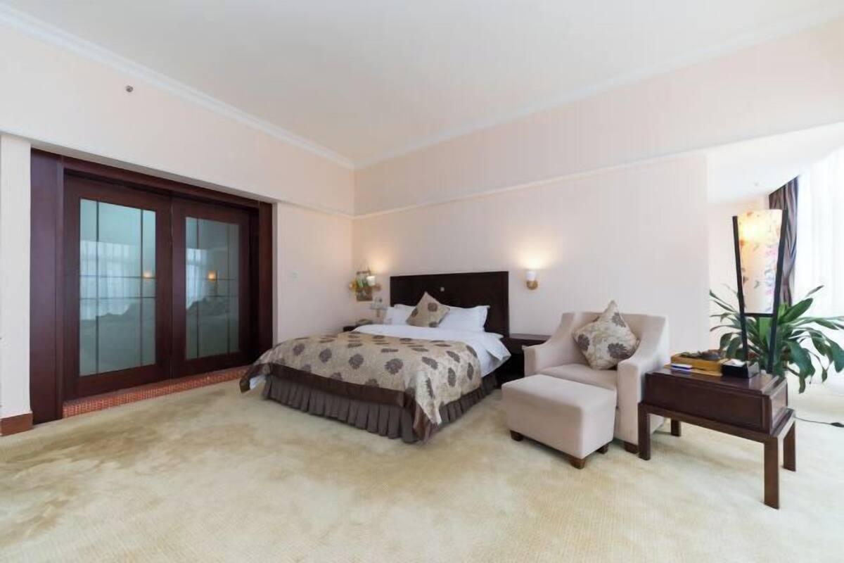 Ein Schlafzimmer mit Bett, Stuhl, Nachttisch, Spiegel und einer Schiebetür.
