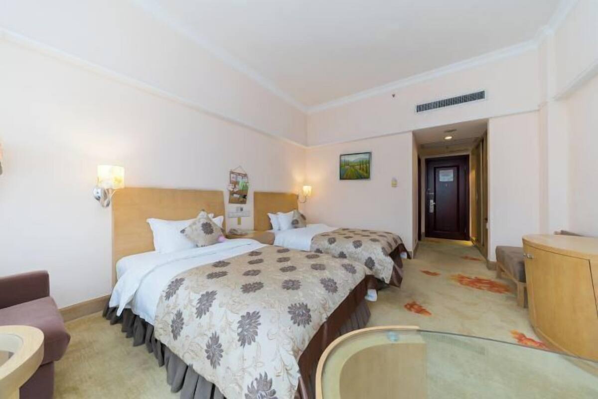 Ein Hotelzimmer mit zwei Betten, einem Schreibtisch, einem Stuhl und einem Schrank.