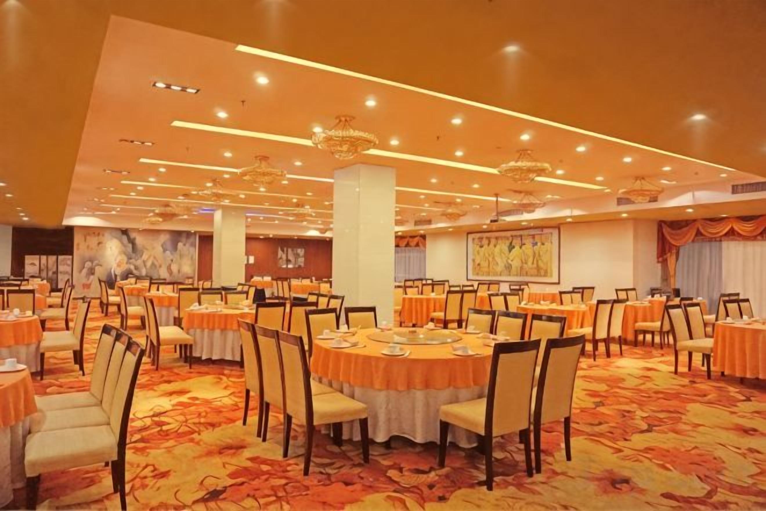 A banquet hall with round tables, chairs, and a carpeted floor.