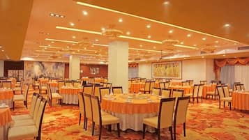 A banquet hall with round tables, chairs, and a carpeted floor.