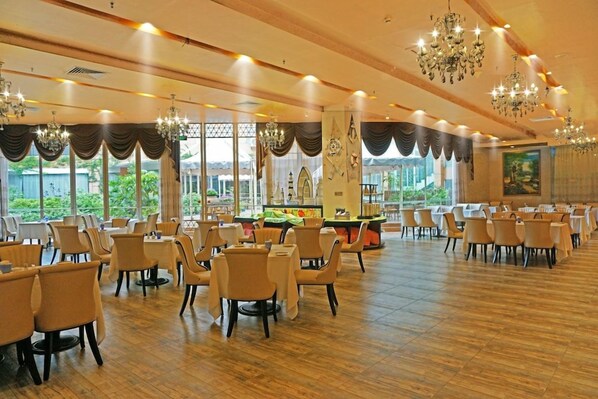 A spacious dining area with multiple tables and chairs, large windows, and chandeliers. - University Town International Hotel (Guangzhou)
