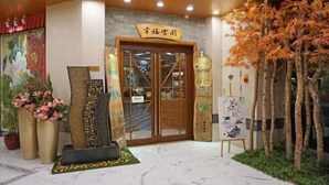 A traditional Japanese-style entrance with a wooden door, a sign above it, and a decorative tree to the right. - University Town International Hotel (Guangzhou)