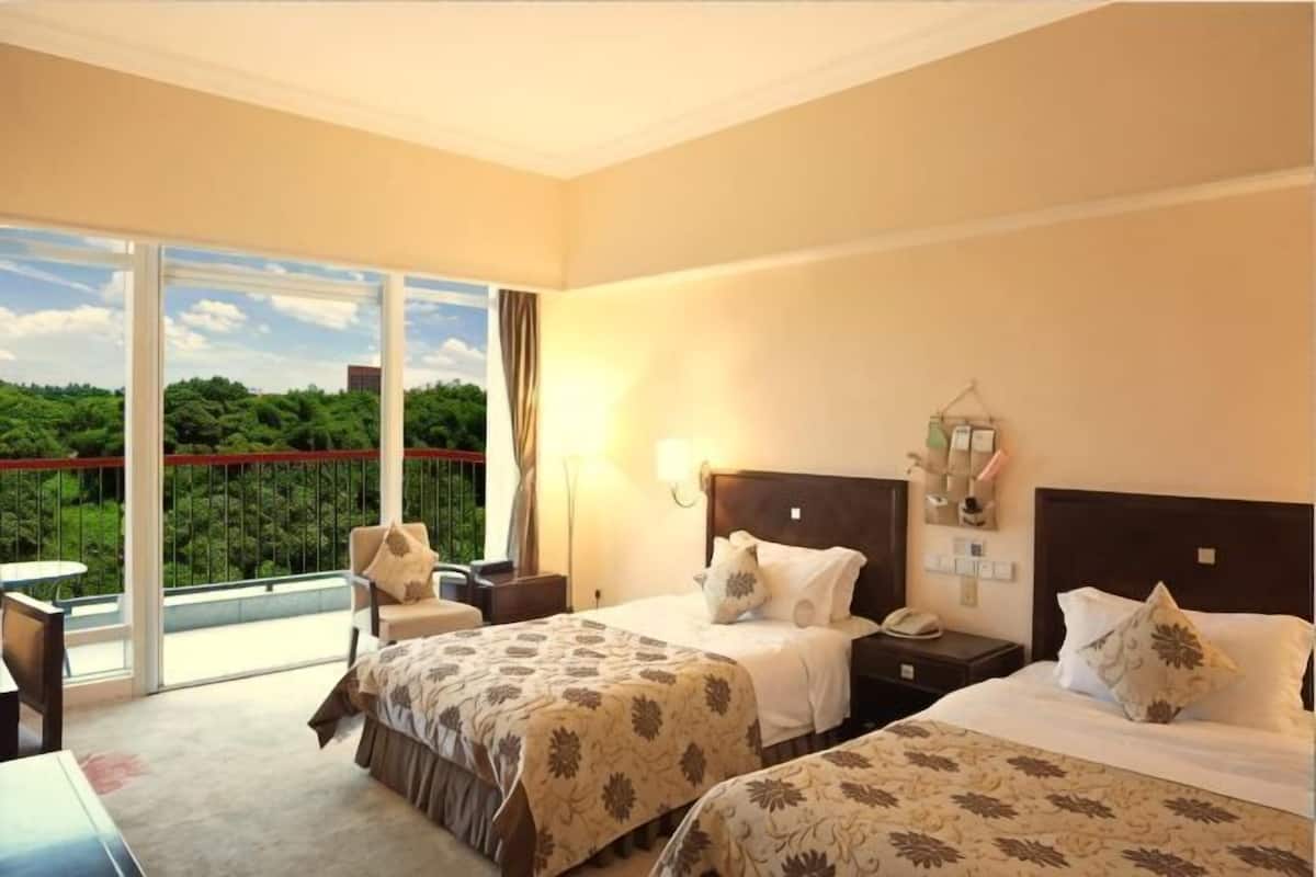 Ein Hotelzimmer mit zwei Betten, einem Balkon, einem Schreibtisch und einem Stuhl.
