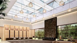 A spacious lobby with a high ceiling, modern pendant lighting, a reception desk, seating area, and large windows. - University Town International Hotel (Guangzhou)