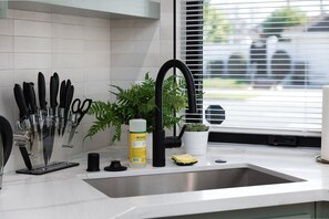 A kitchen with a stainless steel sink, a knife block, a bottle of dish soap, a sponge, and a potted plant. - 2BR Midtown townhome - Walk to Golden 1 & Capitol (Sacramento)