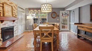 A dining area with a brick fireplace, a wooden dining table, and chairs.