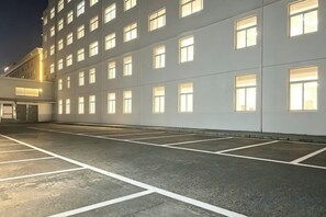 A parking lot with marked spaces and a building with multiple windows in the background.