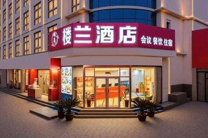A hotel with a red sign, a reception area, and a modern interior visible through the glass doors.