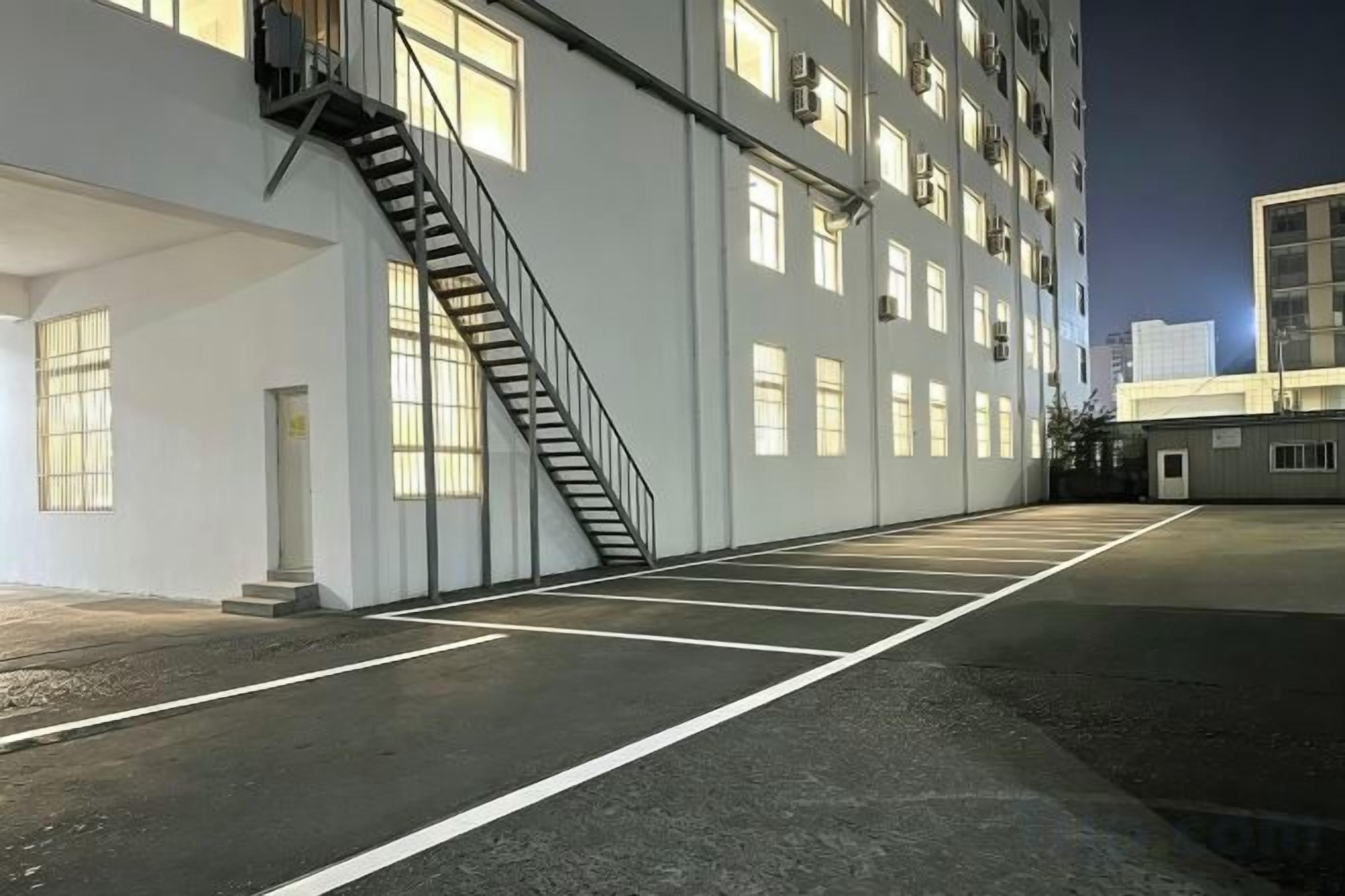 A building with a long, empty parking lot and a staircase leading to the entrance.