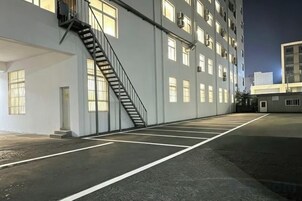 Un edificio con un estacionamiento amplio y vacío, y una escalera que lleva a la entrada.