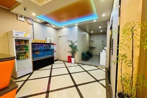 Vestíbulo de hotel con máquina expendedora, mostrador de recepción y zona de recepción.