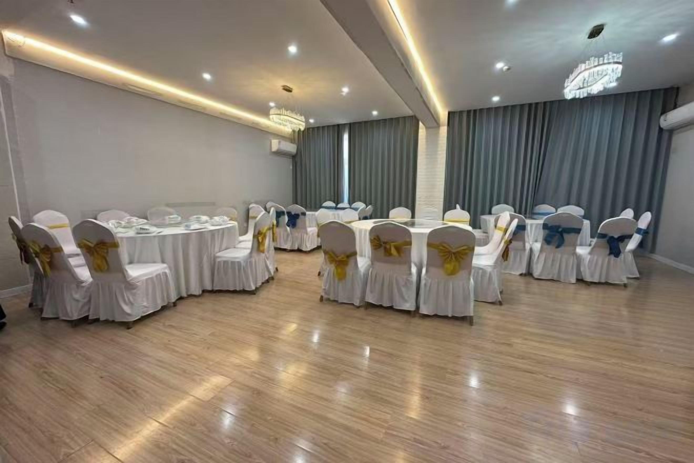 Un salón de conferencias con mesas y sillas redondas, equipado con mesas, sillas y un candelabro.