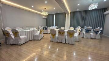 Un salón de conferencias con mesas y sillas redondas, equipado con mesas, sillas y un candelabro.