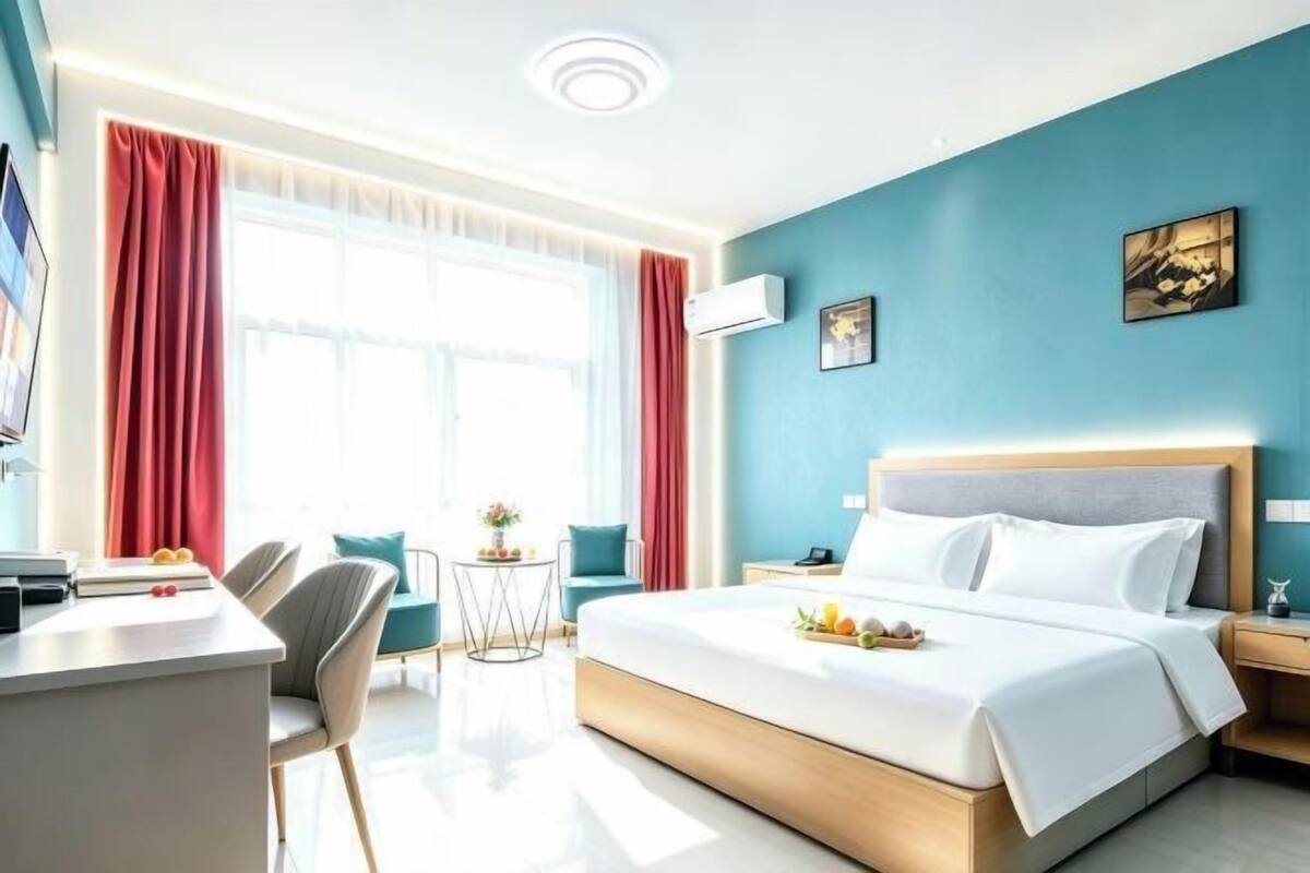 Een hotelkamer met een bed, bureau, stoel en een kleine tafel met een vaas.