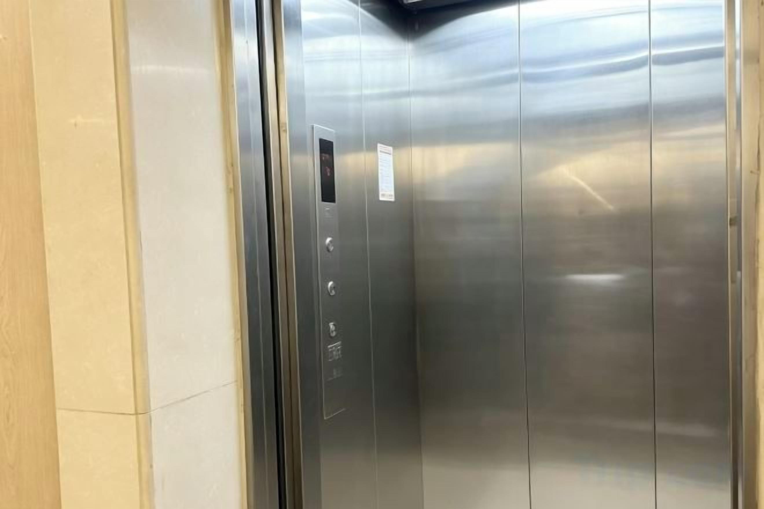 An elevator with metallic walls and a control panel with buttons.