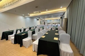 Ein Konferenzraum mit Tischen, Stühlen, einer Kristallleuchtre und Blick durch einen Vorhang.