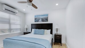 A bedroom with a bed, two bedside tables, a ceiling fan, an air conditioner, and a picture on the wall. - Spacious 1 Bedroom APT at the beach (Hollywood)