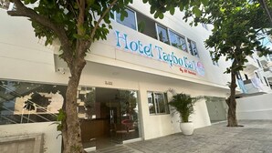 A hotel named "Hotel Taybo Kai" with a modern facade, large windows, and a potted plant in front. - Taybo Kai Hotel by St Hoteles (Santa Marta)