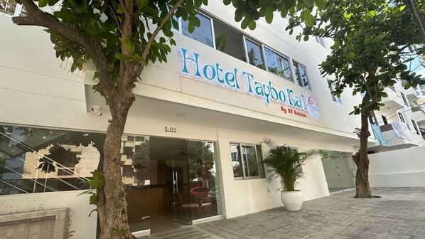 A hotel named "Hotel Taybo Kai" with a modern facade, large windows, and a potted plant in front. - Taybo Kai Hotel by St Hoteles (Santa Marta)
