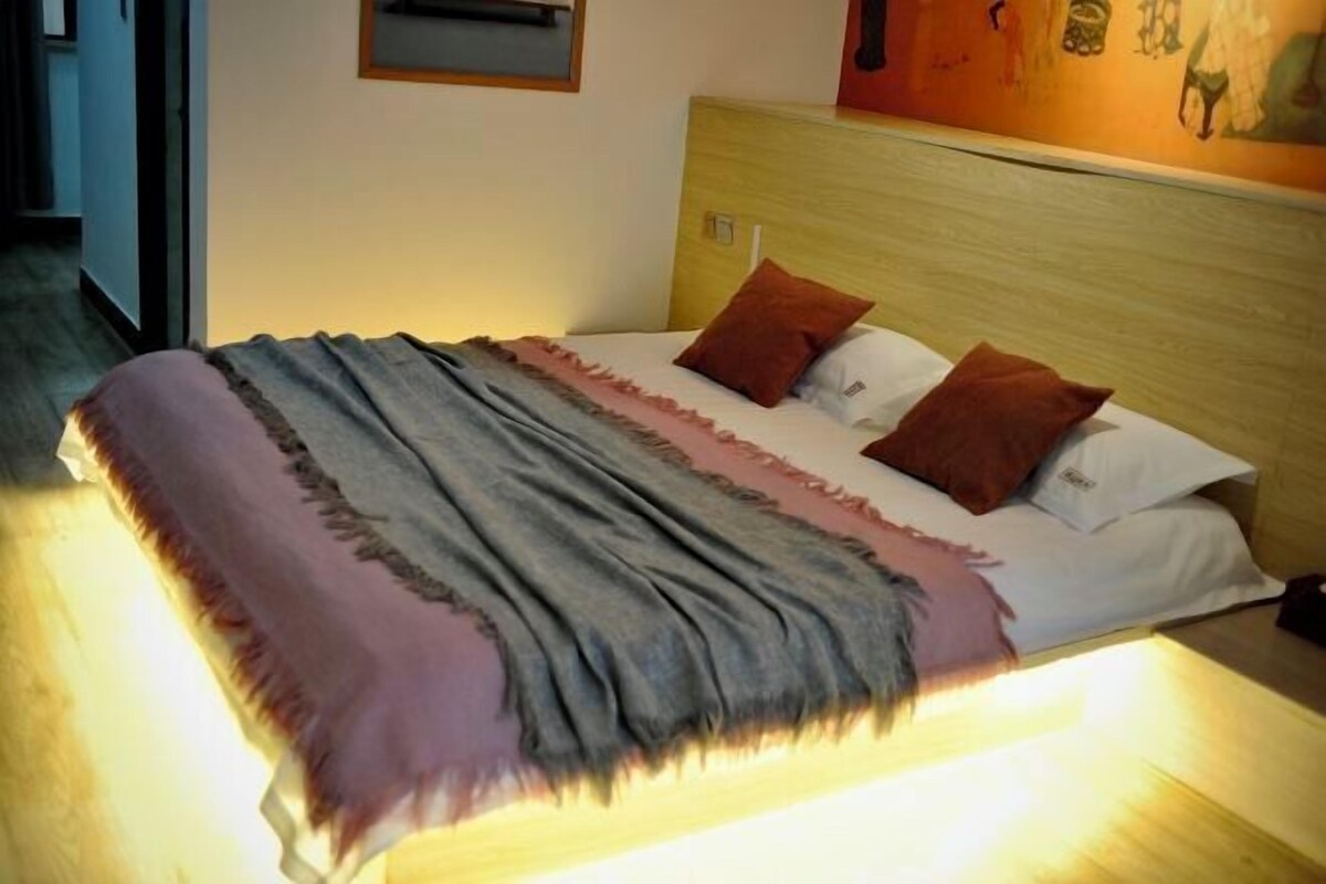 A bed with a headboard, a blanket, and two pillows.