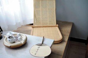 A tatami mat room with a low table, a fan, and a tray with teacups. - Wuyishan Half Mountain and Half Water (Zen culture theme) Hotel (Wuyishan)