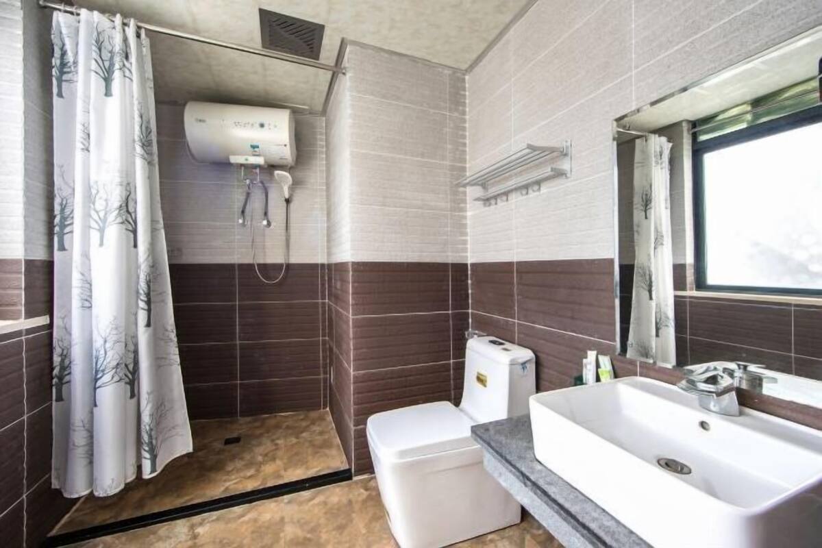 A bathroom with a shower, toilet, sink, and a window.