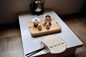 A wooden tray with a teapot, cups, and a fan on a table. - Wuyishan Half Mountain and Half Water (Zen culture theme) Hotel (Wuyishan)