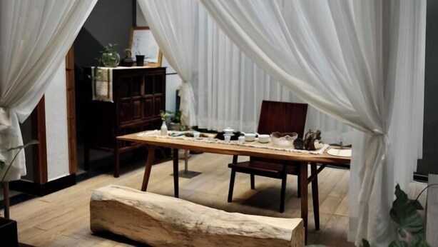 Un comedor con una mesa de madera dispuesta para cuatro personas, rodeado de cortinas blancas.