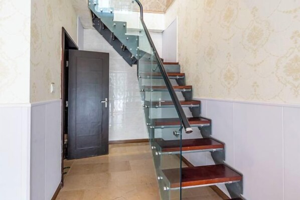 A modern staircase with glass railings and wooden steps, leading to a door at the top. - Simianshan Hotel (Chongqing)