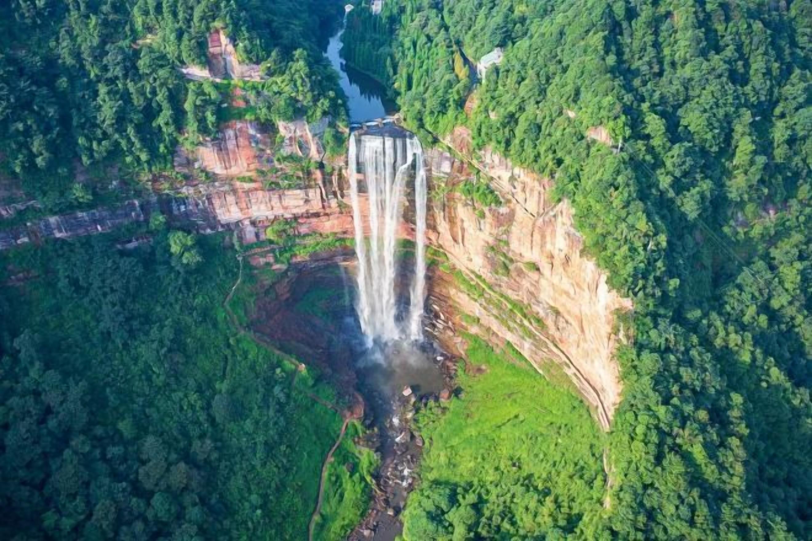 An aerial view of a waterfall surrounded by dense forest.