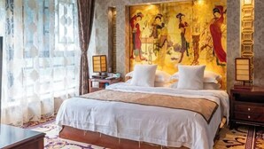 A hotel room with a large bed, a decorative wall painting, a nightstand, and a lamp. - Simianshan Hotel (Chongqing)