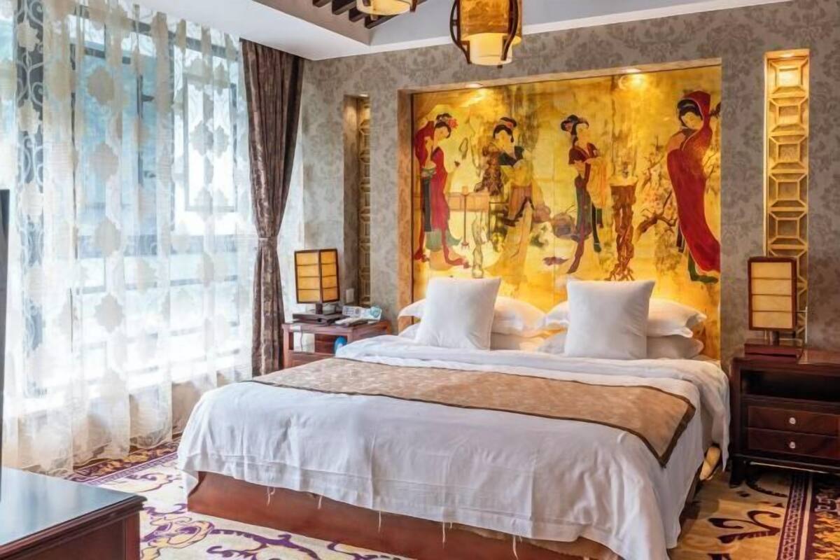 Una habitación de hotel con una cama grande, un cuadro decorativo en la pared, una mesita de noche y una lámpara.