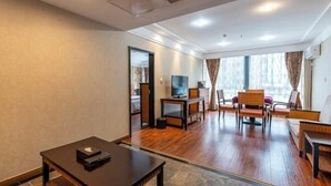 A modern hotel room with a wooden floor, a TV, a sofa, and a dining table. - Simianshan Hotel (Chongqing)