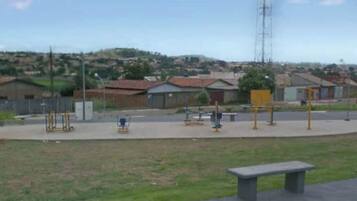 A park with exercise equipment, a bench, and a playground.