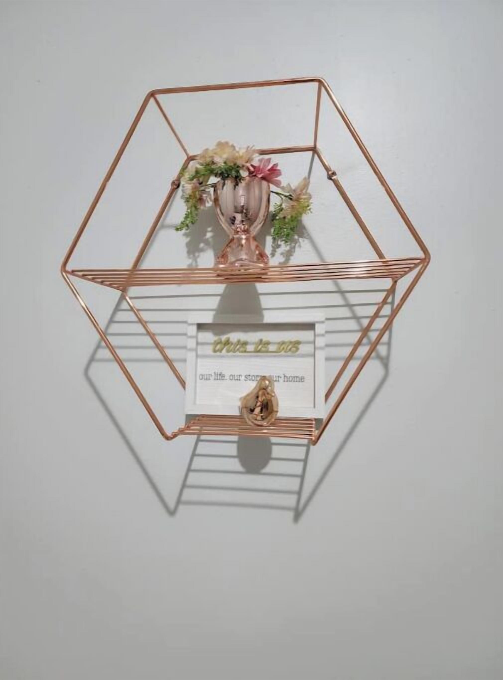 A hexagonal metal shelf with a vase of flowers and a framed sign that reads "Our life, our story, our home."