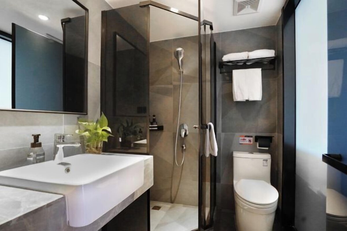 A modern bathroom with a glass-enclosed shower, a white sink, and a toilet.