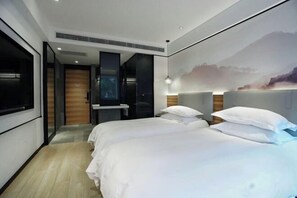 A modern hotel room with a large bed, a desk, and a view of a mountain.