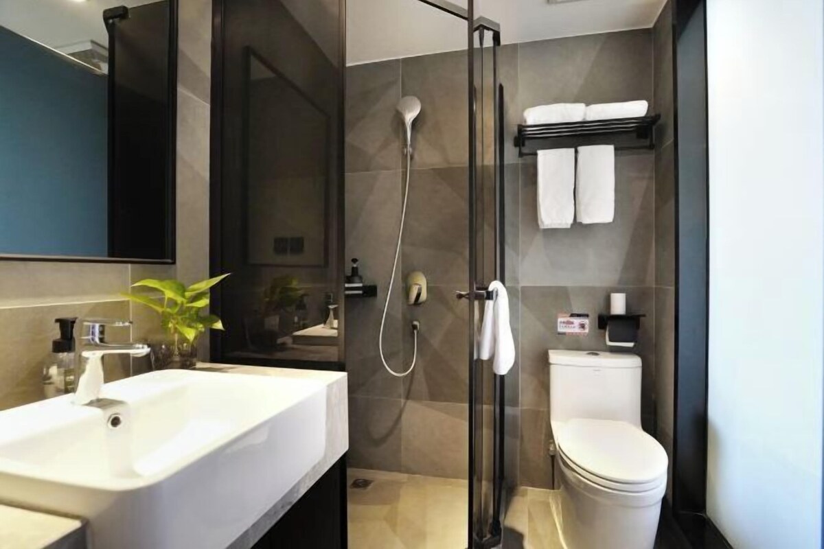 A modern bathroom with a glass-enclosed shower, a white sink, and a toilet.