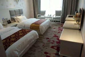 Habitación de hotel con dos camas, un escritorio, una silla y una mesita.