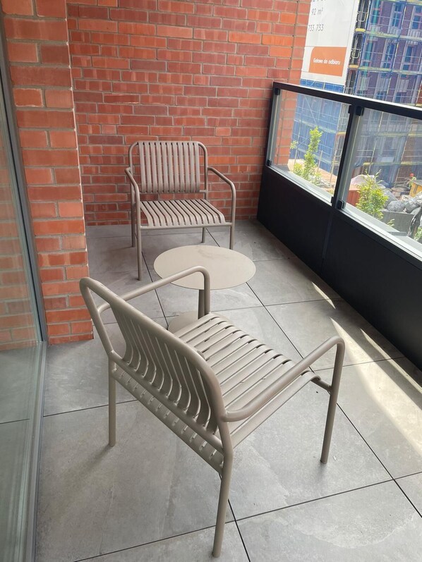 Un balcon avec deux chaises en métal et une petite table ronde.