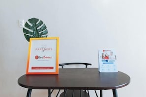 A framed sign on a table with text and logos, a RedDoorz brochure, and a large green leaf decoration. - RedDoorz @ Isabelle Tourist Hotel Hinatuan (Hinatuan)