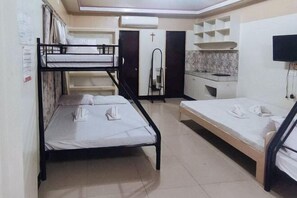 A dormitory room with bunk beds, a kitchenette, a TV, and a cross on the door. - RedDoorz @ Isabelle Tourist Hotel Hinatuan (Hinatuan)